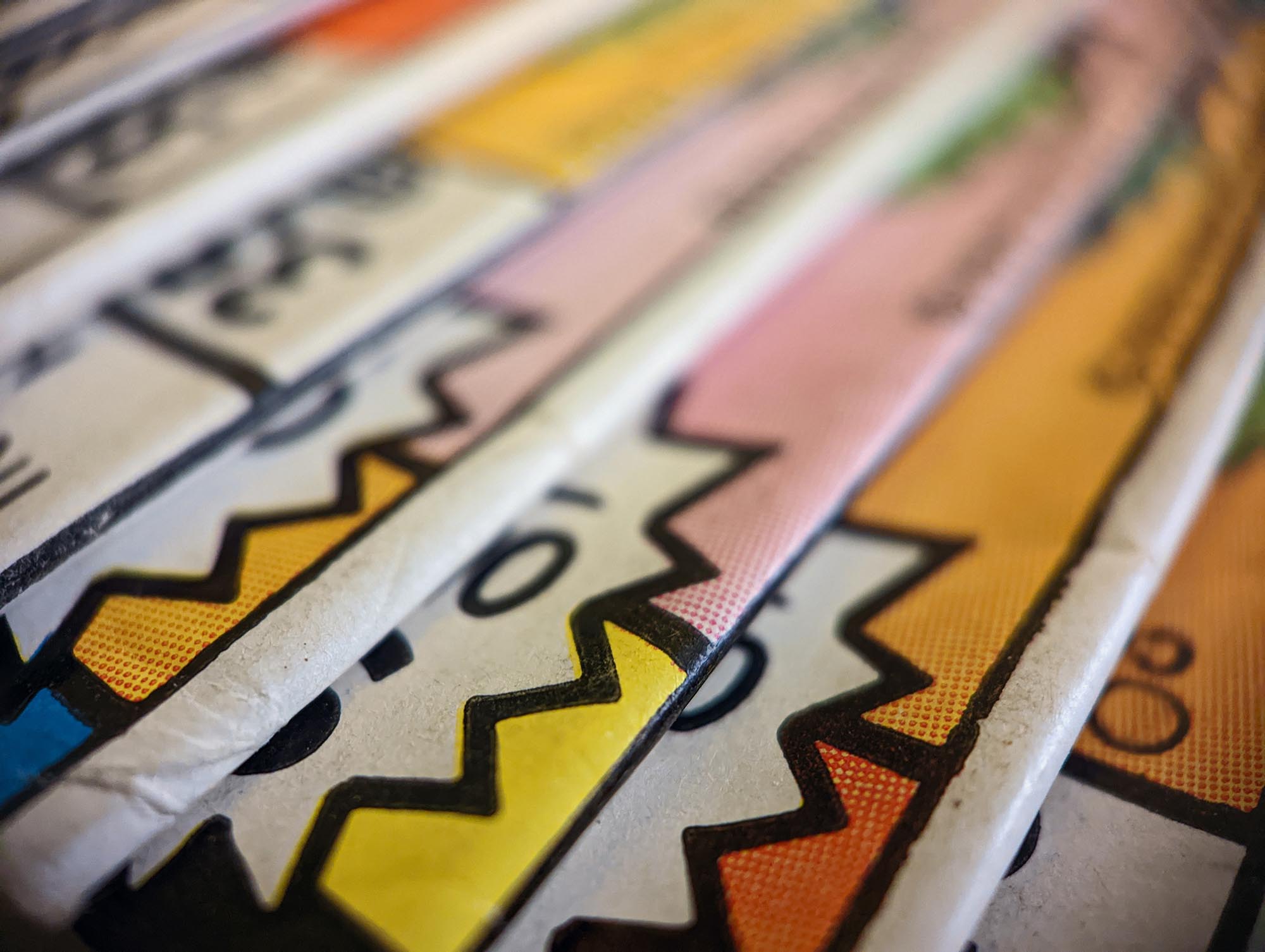 Closeup view of an old comic book collection stacked in a pile creates colorful background paper texture with abstract shapes