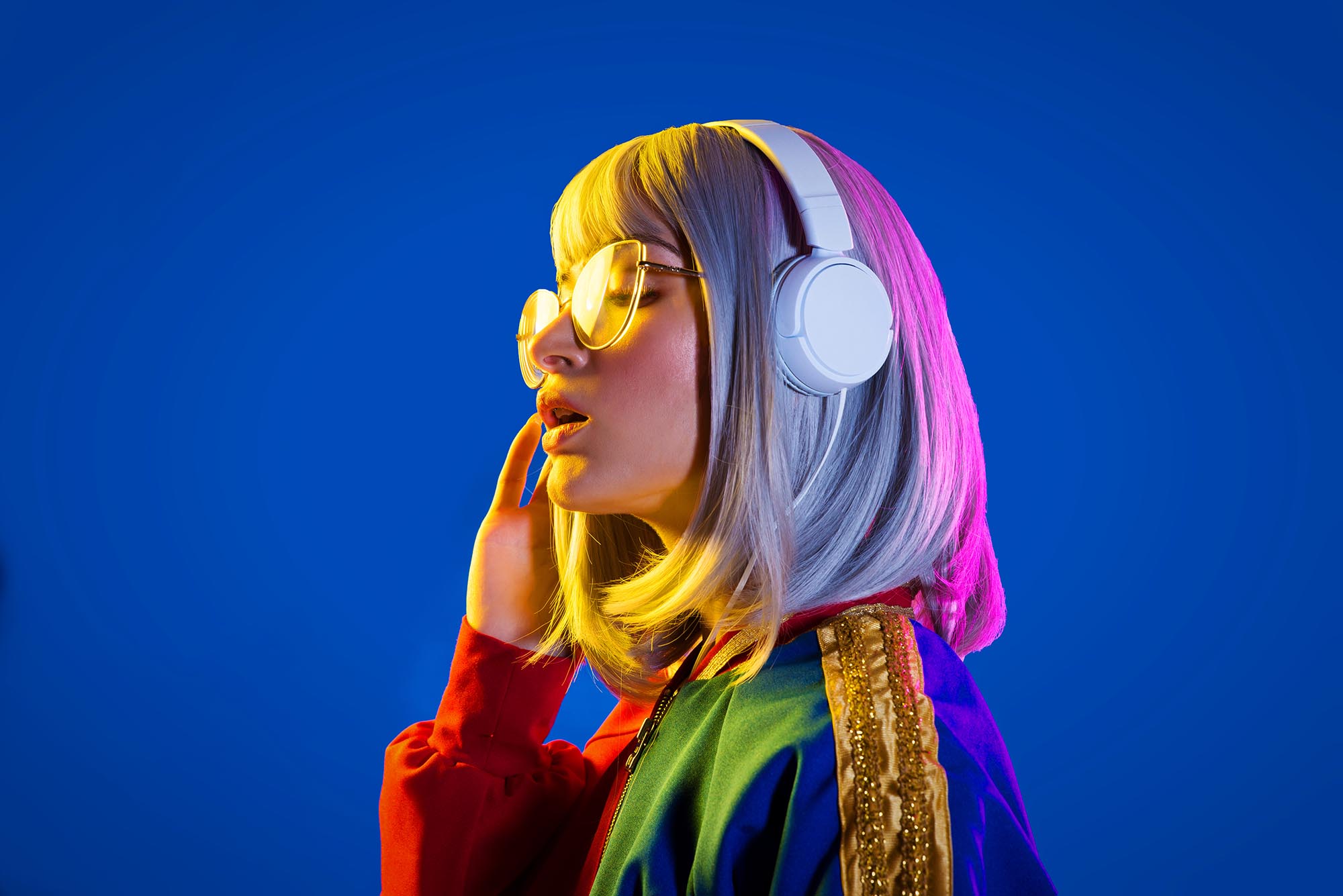 woman with stylish clothes wearing headphones on blue background