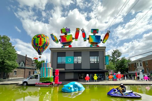 A photo of the Asher building modified using generative AI to add colorful robots, a hot air balloon, water, a jet ski, and a large cake.