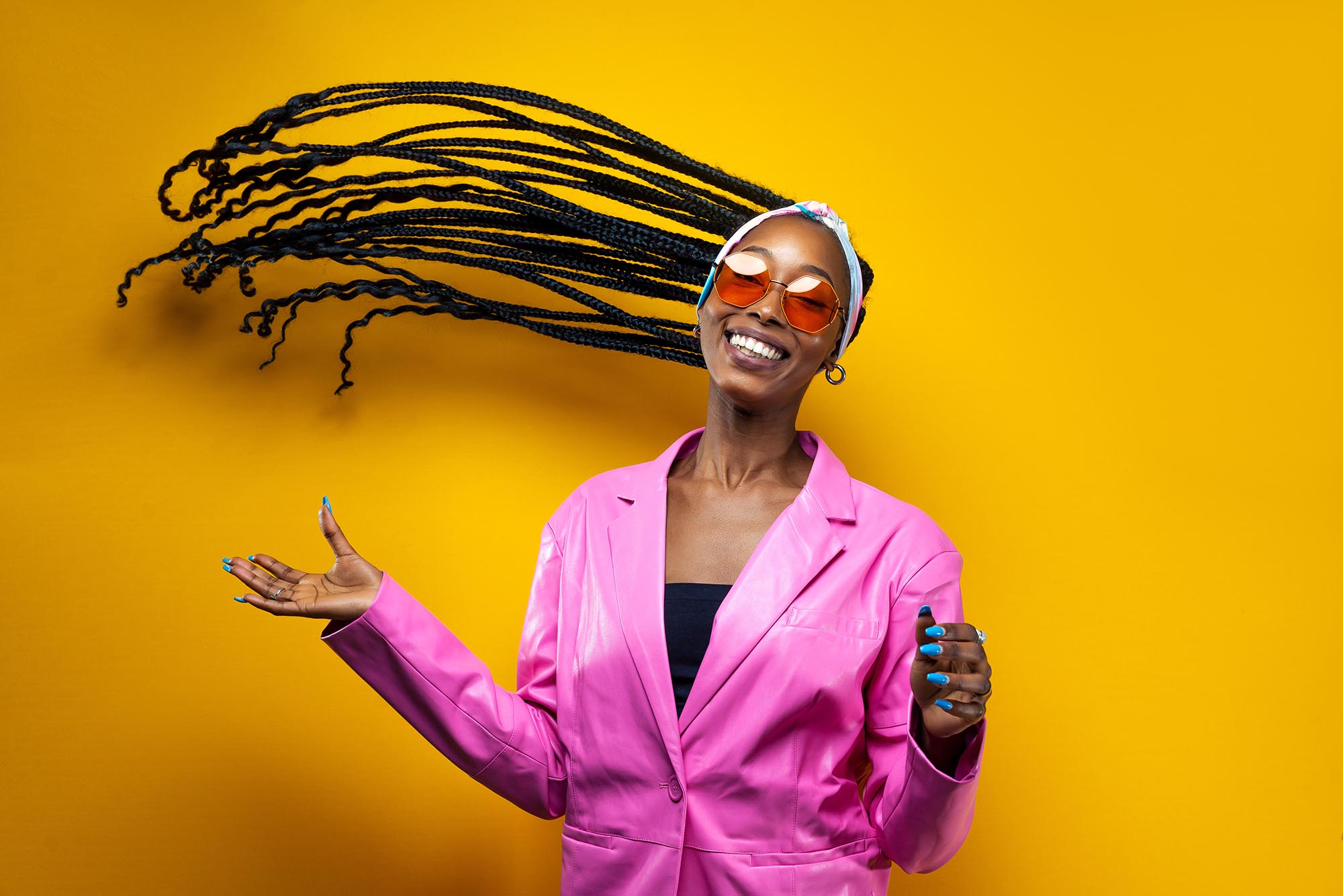 Beautiful african american woman smiling and flipping hair to the side, wearing stylish pink clothes on a yellow background