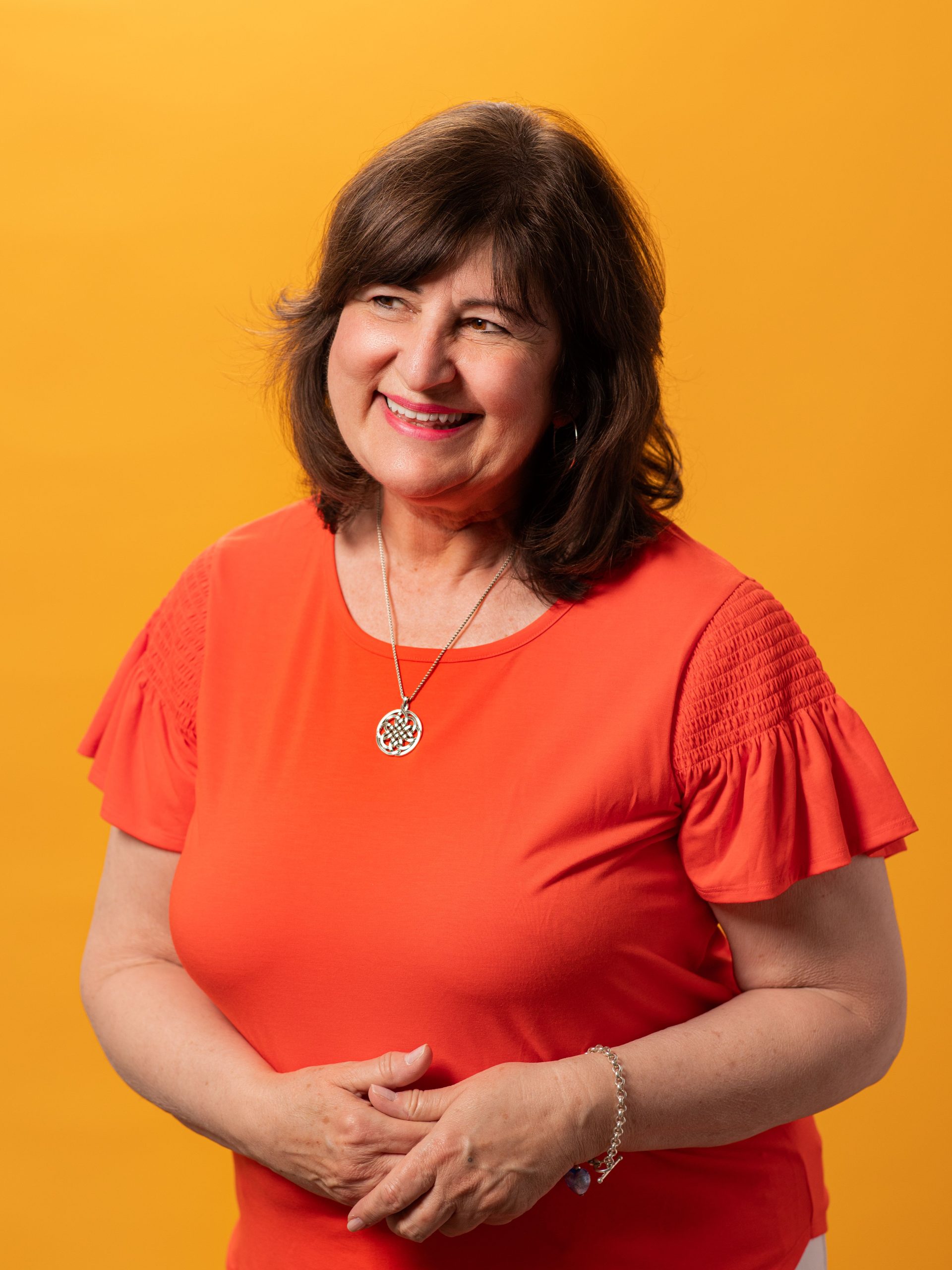 Marina McQueary, Asher Agency Senior Planner/Buyer wearing bright orange blouse