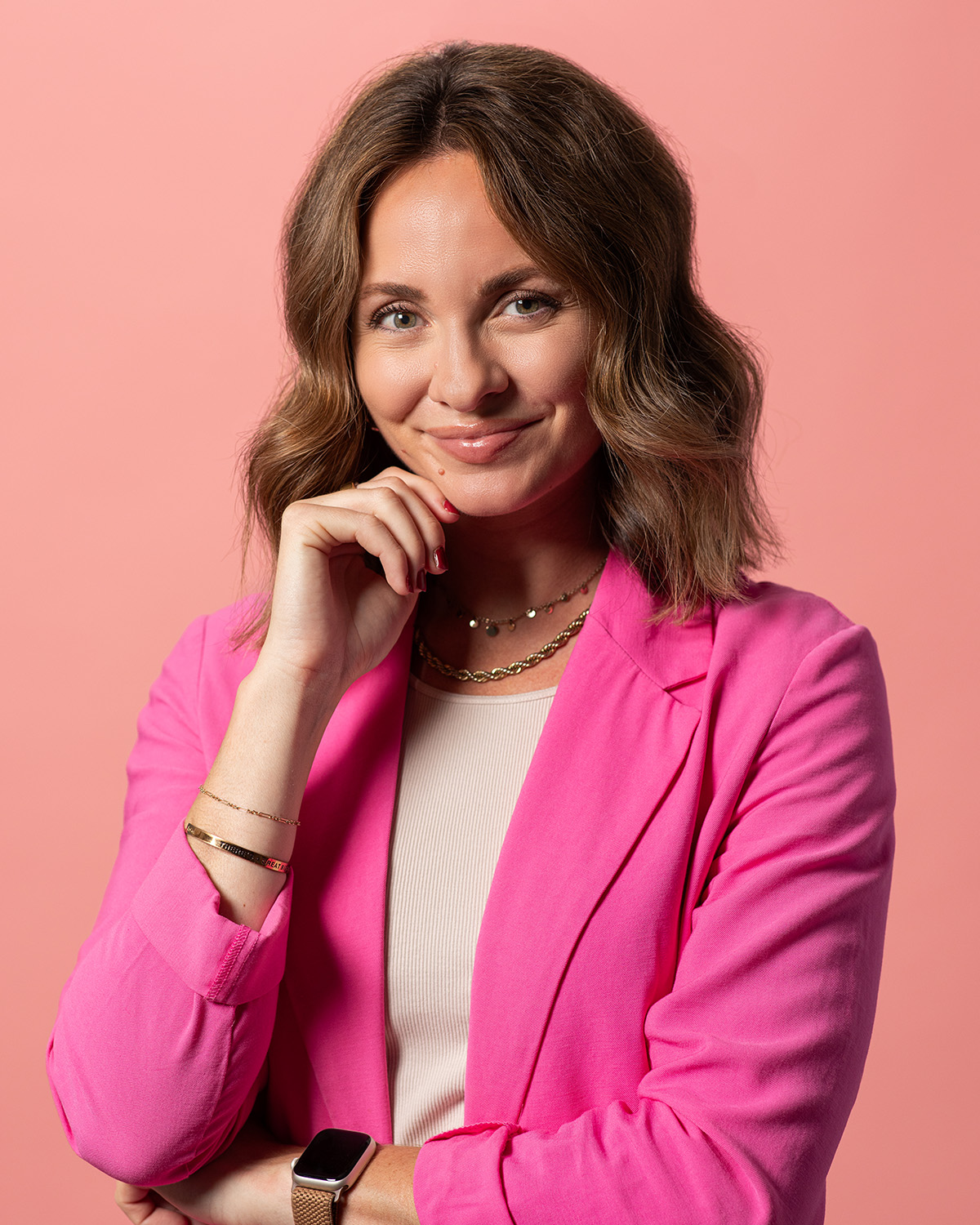 Ashley Miller, Asher Account Executive, with pink blazer and resting hand against chin