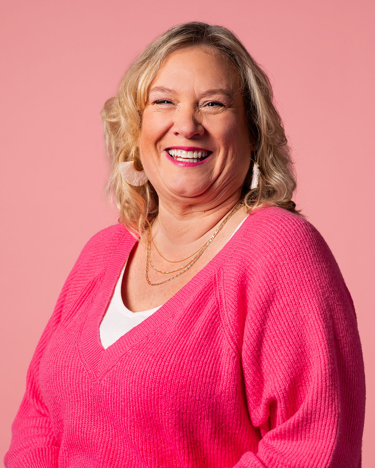 Mary Kinder, Asher Agency Senior Copywriter, laughing wearing bright pink sweater