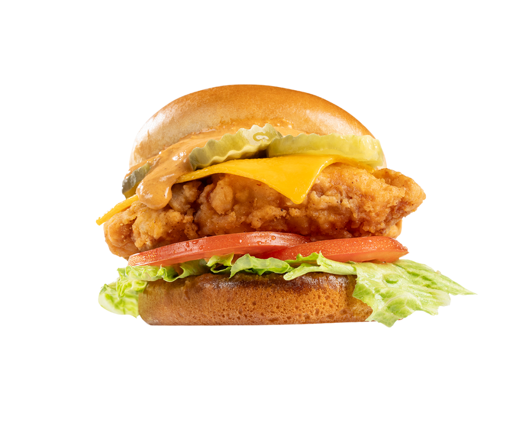 A chicken sandwich shot at a lower angle. Between the brioche buns is lettuce, tomato, crispy chicken, cheddar cheese, pickles and a chipotle aioli sauce that is dripping down from above the pickles.