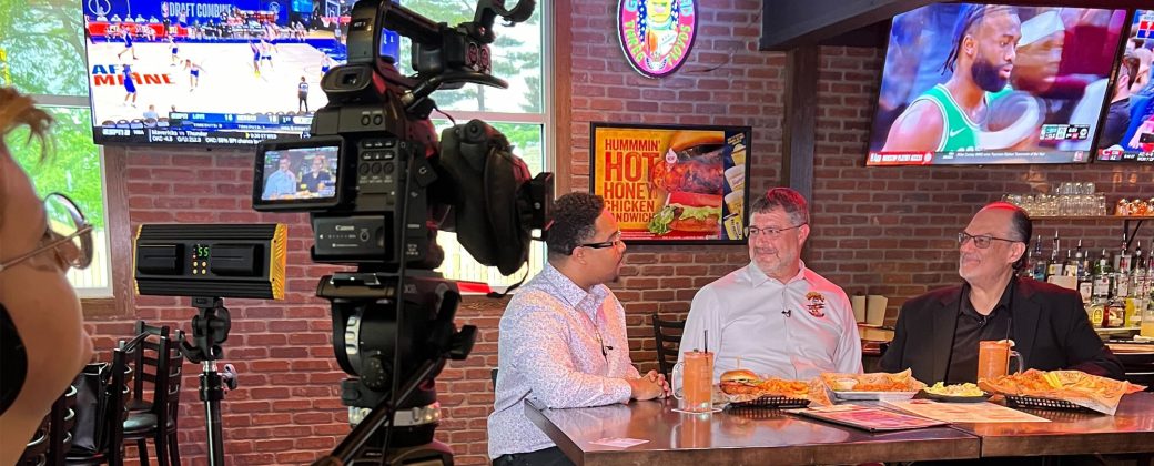 reporter talking with two business owners at a pub
