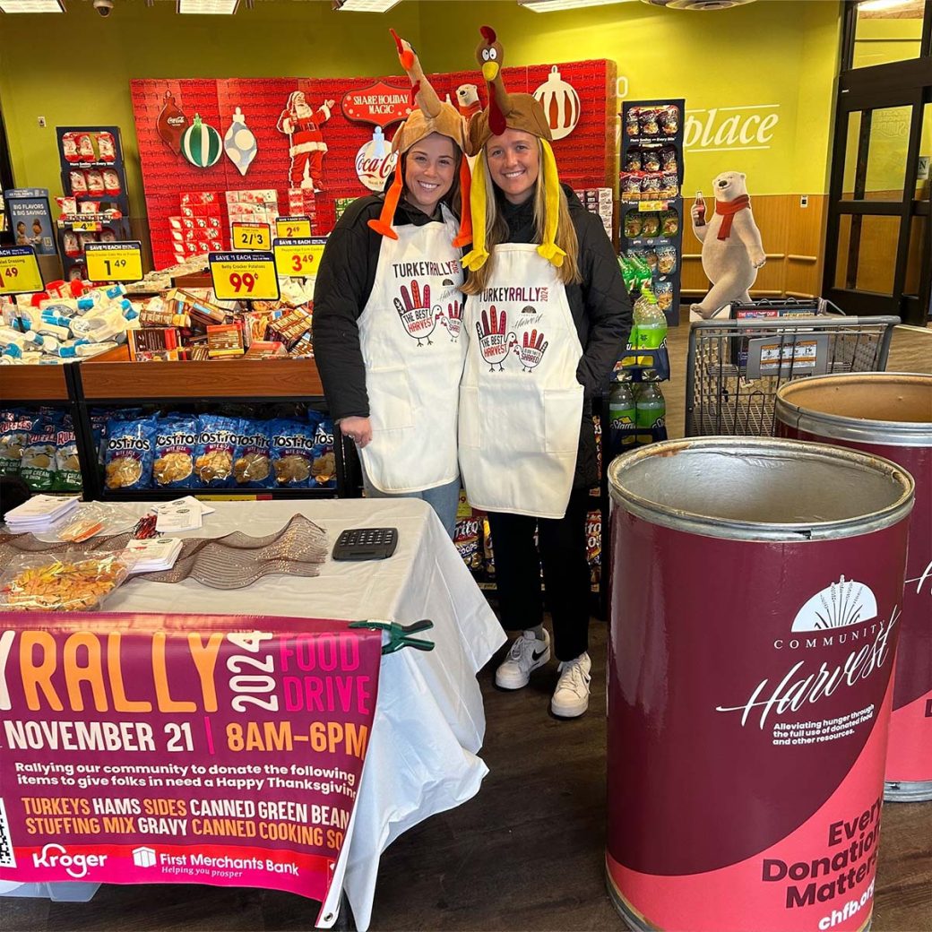 Sarah Frazier and Emily Land volunteering for the Community Harvest Food Bank turkey rally. They both have turkey hats on their heads.