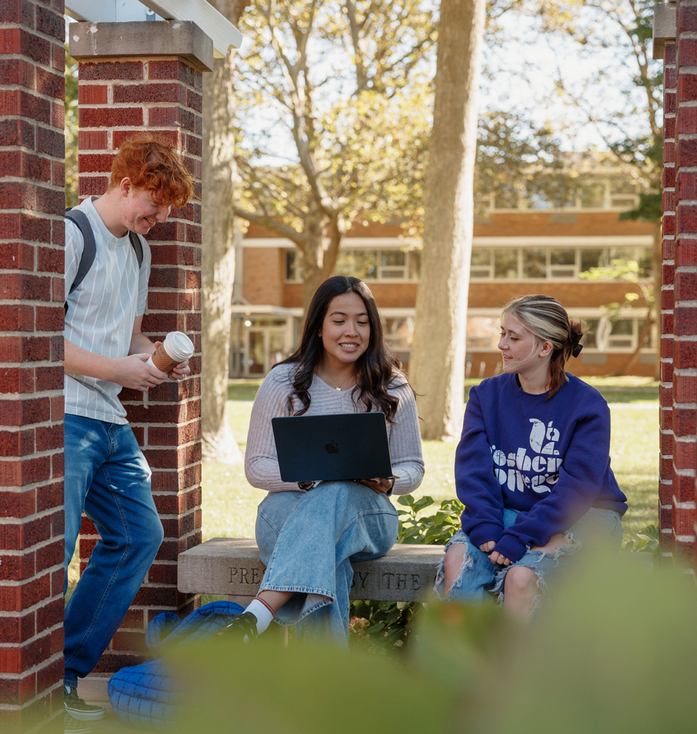 three college students smiling and talking